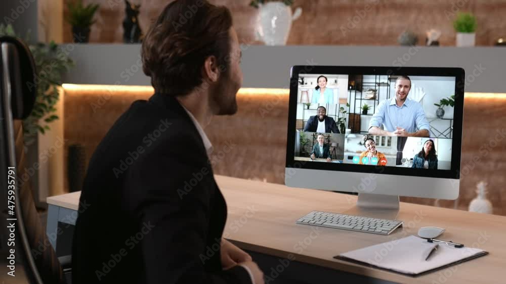 Video call, online conference. Over shoulder view of business man, on computer screen with multinational group of successful business people, virtual business meeting, telecommunication concept Video call, online conference. Over shoulder view of business man, on computer screen with multinational group of successful business people, virtual business meeting, telecommunication concept