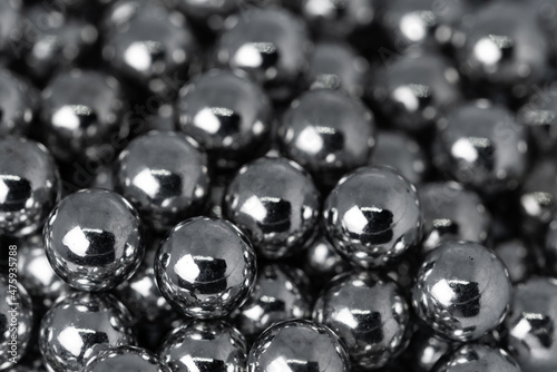Metal balls arranged side by side to form an organized structure. Macro scale photo with shallow depth of field. Glossy surface with a metallic sheen.