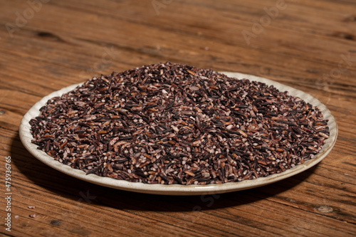 Place the black rice in the plate or bowl on the wood grain table