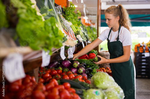 Canvas Print Young girl seller in uniform working in supermarket at her first job, checking o