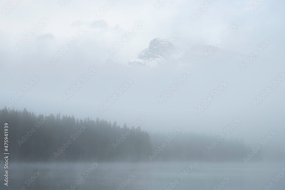 A mysterious morning at Two Jack Lake in Banff as fog shrouds most of the scene with just a peak poking out above the mist.