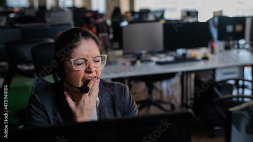 Business woman yawns at her desk in the office.