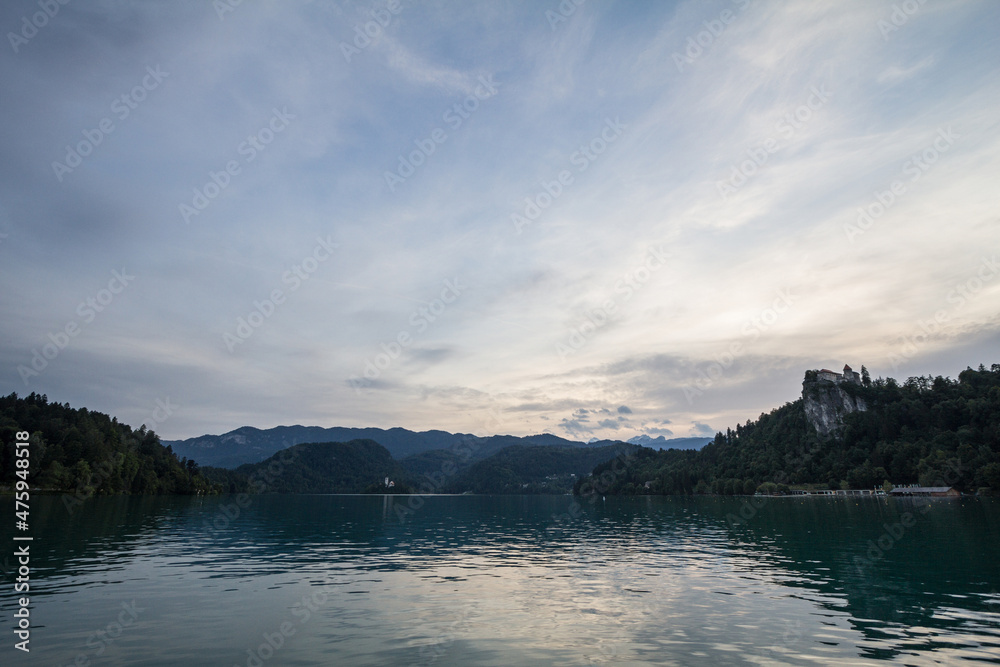 Panorama of the Bled lake, Blejsko Jezero, with its castle, Blejski Hrad, during a sunny sunset in summer with the mountains of Julian alps. Bled Castle is a major monument of Slovenia.....