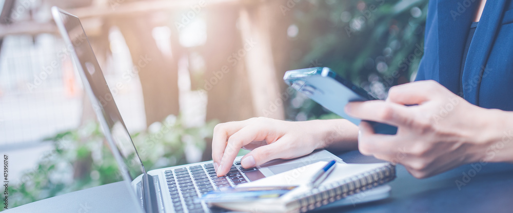 Business woman working with a laptop computer and uses a cell phone in the office.