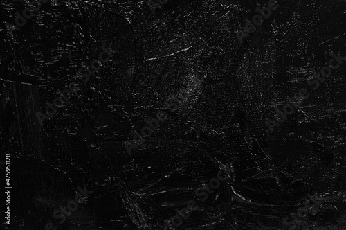 Dark creative background - rough linen canvas unevenly covered with black primer, reflections of light. Toning, blurring, selective focus.