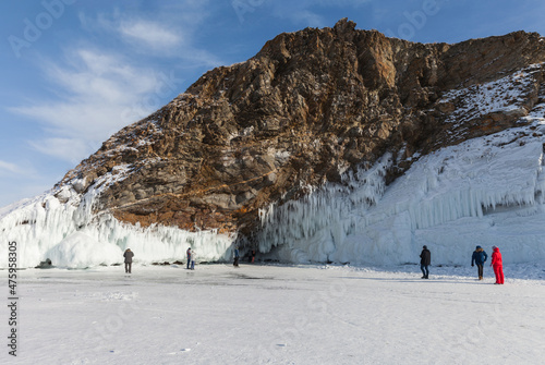 Winter Baikal Lake. Tourists travel on the ice of the frozen lake and take pictures of the beautiful icy rocks of Olkhon Island