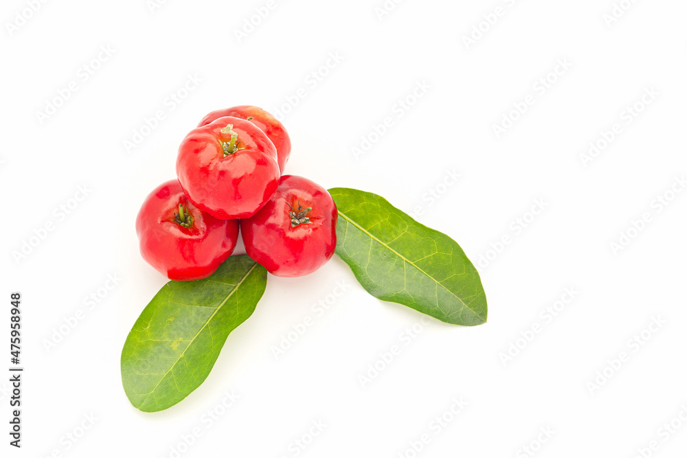 Pile of ripe red acerola cherries and green leaves isolated on a white background
