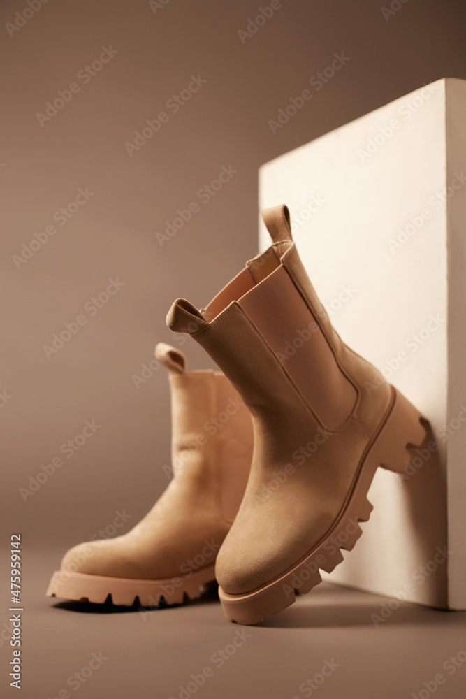 Trendy boots with wooden wall. fashion female shoes still life