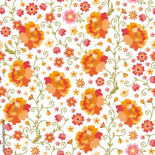 Bright native floral embroidered seamless ornament on a white background. Flowers with orange, red, pink and yellow petals, curved light green stems and tiny leaves. Romantic fashion print for fabric.