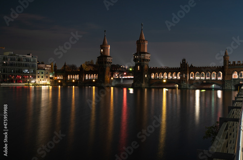 Mesmerizing view of lighted Oberbaum bridge on the coast of river late in the evening in Berlin photo