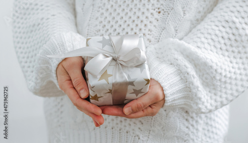 Female hands are holding small gift box. Winter holidays concept New Year Christmas. Selective focus, light background