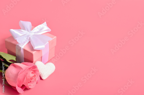 A gift box with a white bow, a rose and a white knitted heart. © Irina Lesovaia