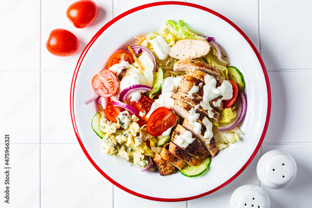 Buffalo chicken salad with blue cheese, tomato, cucumber and ranch dressing, white tile background. - obrazy, fototapety, plakaty 