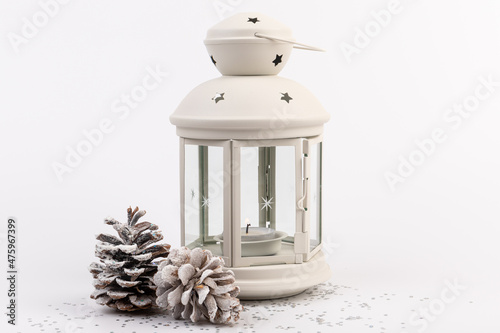 White lantern with candle inside and Christmas decoration on white background. Copy space.