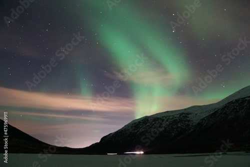 Mesmerizing view of the Aurora Borealis over the mountain in Kvaloya, Arctic region in Norway photo