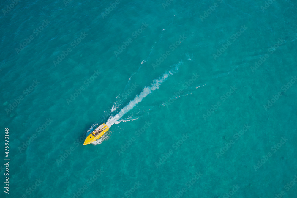 Yellow high speed luxury boat with people fast movement on turquoise water. Boat performance fast movement on clear water aerial view.