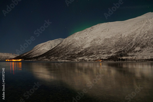 Breathtaking Aurora Borealis over mountain and lake water in Kvaloya, Arctic region in Norway photo