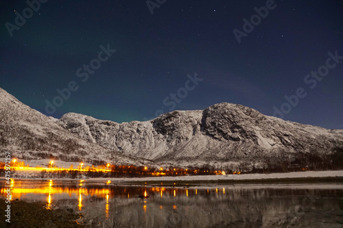 Breathtaking Aurora Borealis over mountain and lake water in Kvaloya, Arctic region in Norway photo