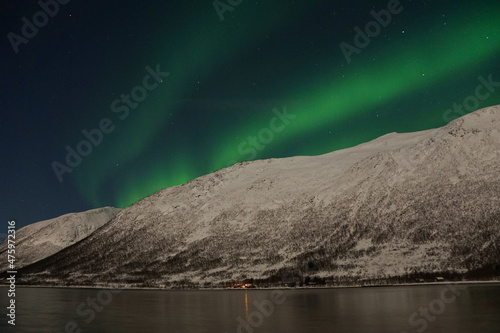 Aurora Borealis over mountain and lake water in Kvaloya, Arctic region in Norway photo