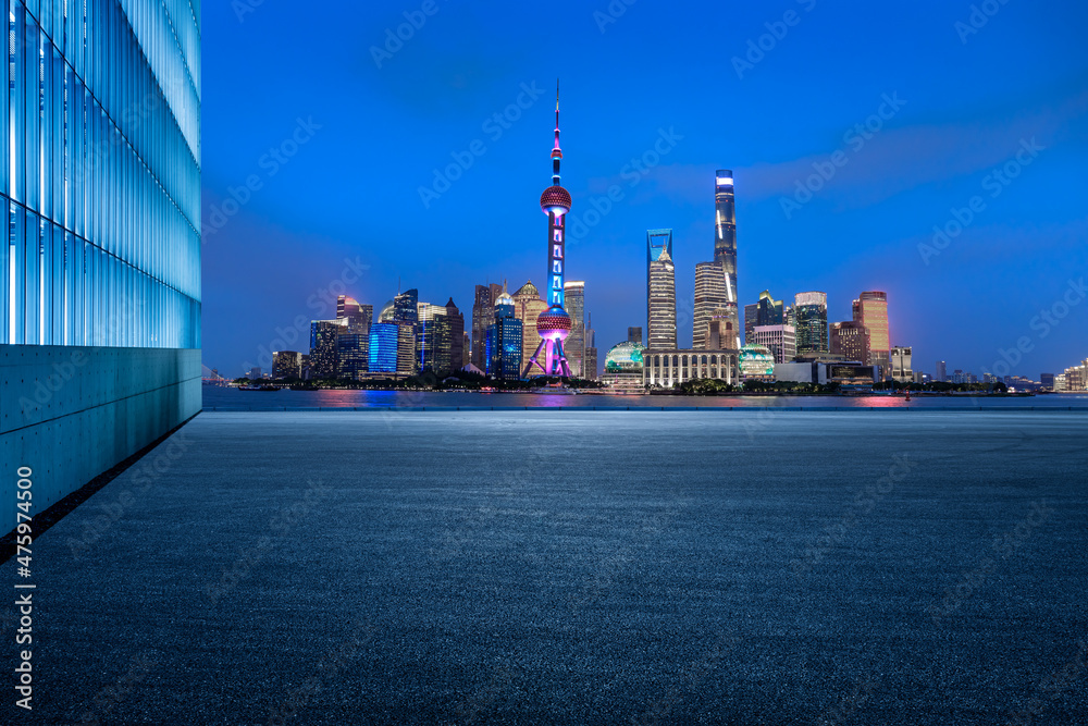 Panoramic skyline and modern commercial buildings with empty road. Asphalt road and cityscape at night.