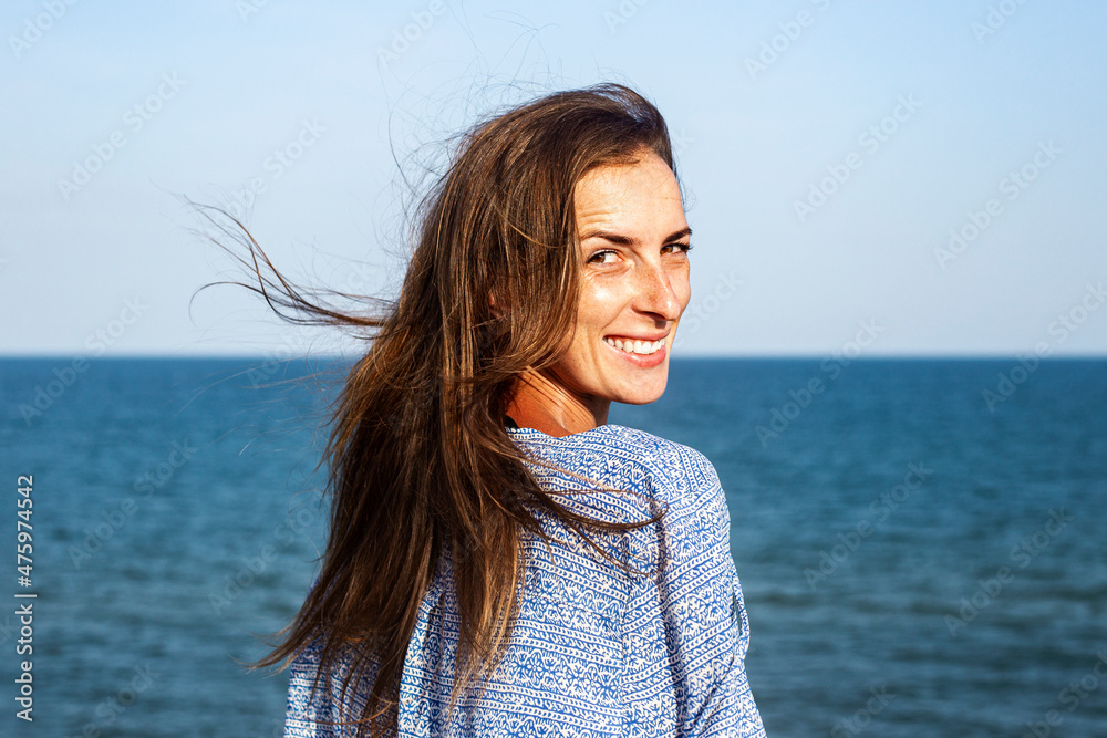 Smiling young woman in dress on the background of the sea.