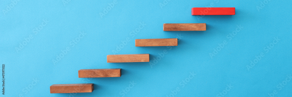 Red block standing over wooden on blue background closeup Red block standing over wooden on blue background closeup