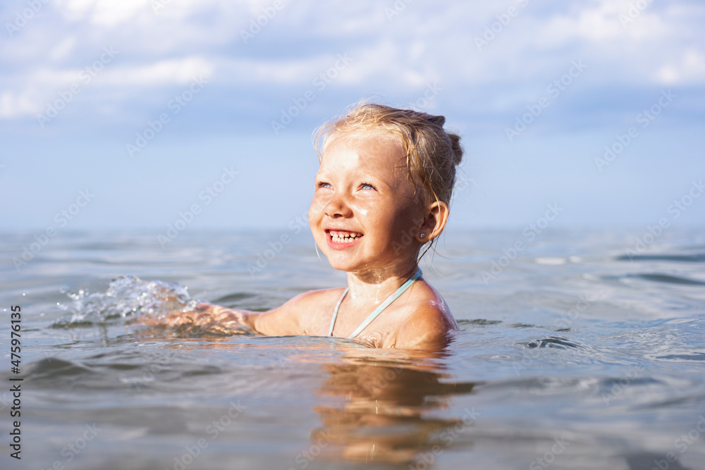 Cheerful smiling child blond girl swimming in the sea on a summer day. Cheerful smiling child blond girl swimming in the sea on a summer day.