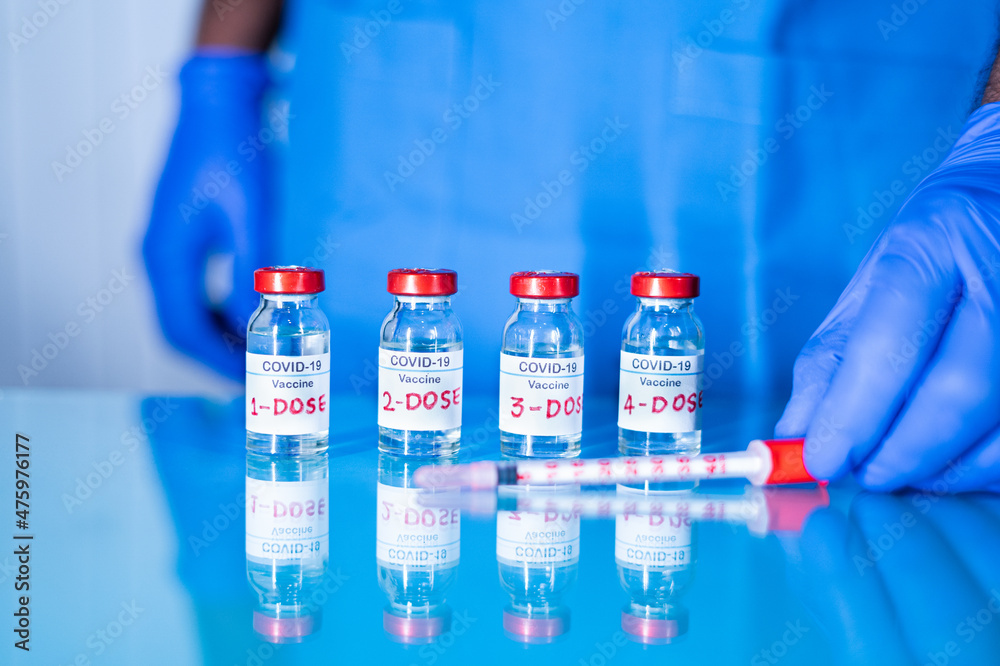 Close up of doctor placing multiple doses of covid-19 or coronavirus vaccine and syringe on table for vaccination to protect againt coronavirus variants or to stop pandemic - obrazy, fototapety, plakaty 