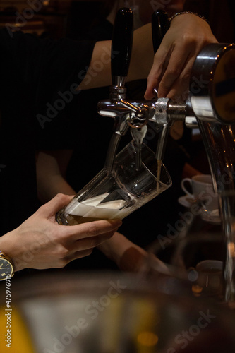the bartender pours beer into a glass 