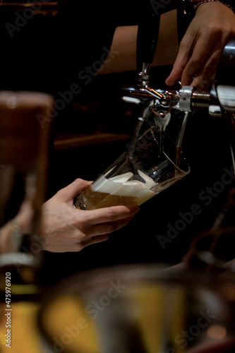 the bartender pours beer into a glass 