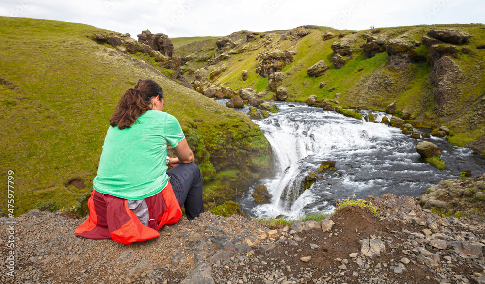 Naklejka premium Woman watching the Skoga river before the Skogafoss waterfall