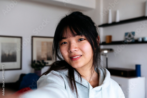 Smiling woman with bangs taking selfie at home