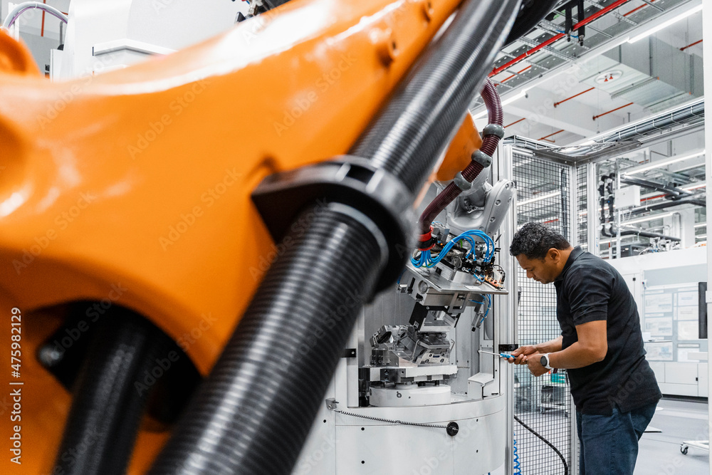 Maintenance engineer repairing robot arm in factory Maintenance engineer repairing robot arm in factory
