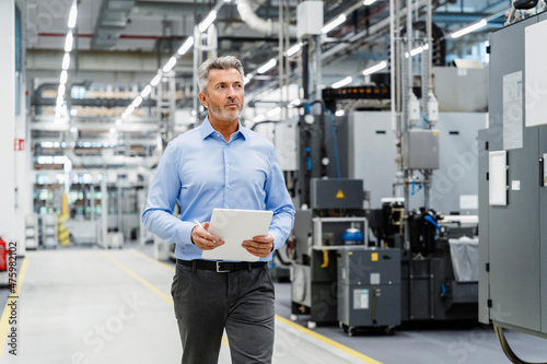 Businessman with tablet PC inspecting automated industry