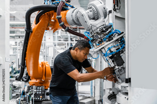 Engineer examining robotic arm in factory photo