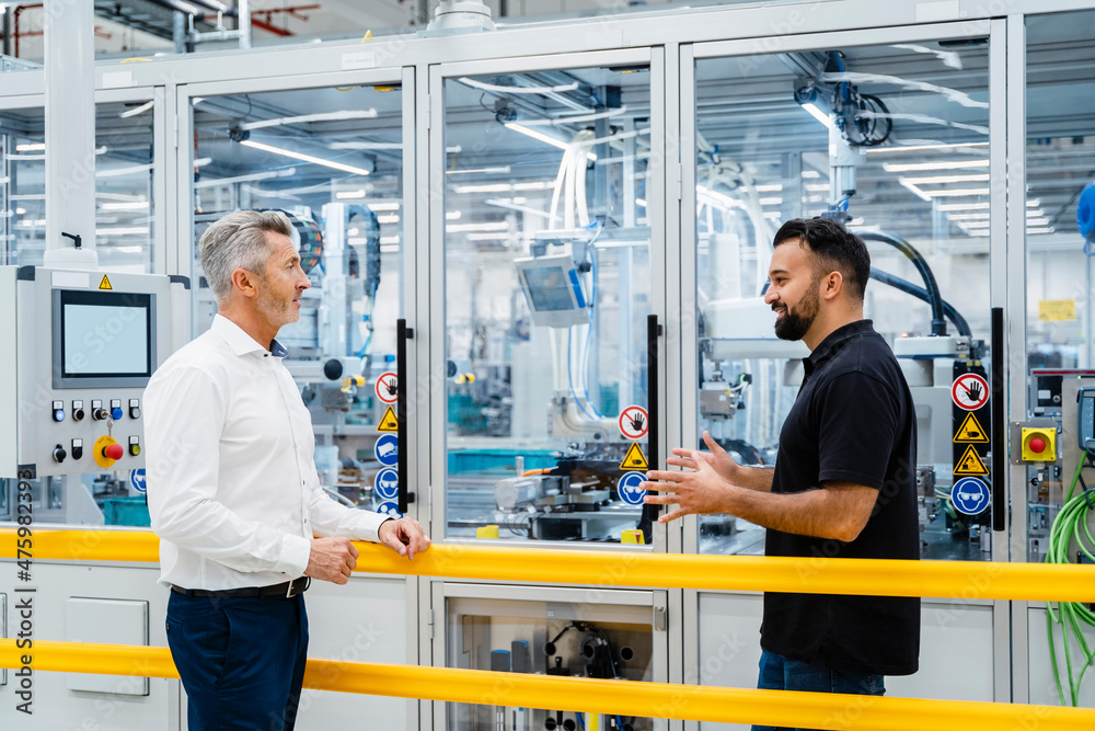 Engineer explaining businessman at automated industrial machinery Engineer explaining businessman at automated industrial machinery