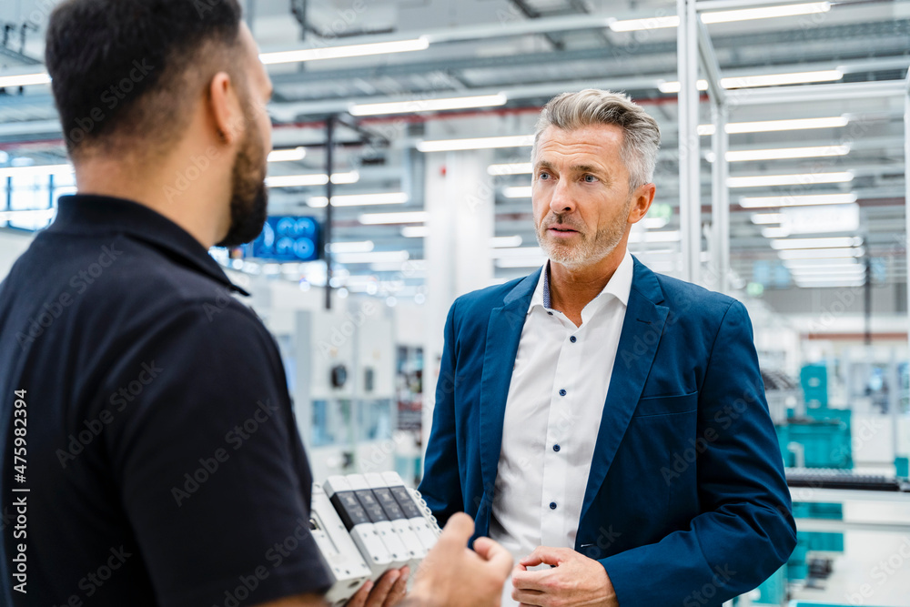Businessman having discussion with maintenance engineer at industry Businessman having discussion with maintenance engineer at industry