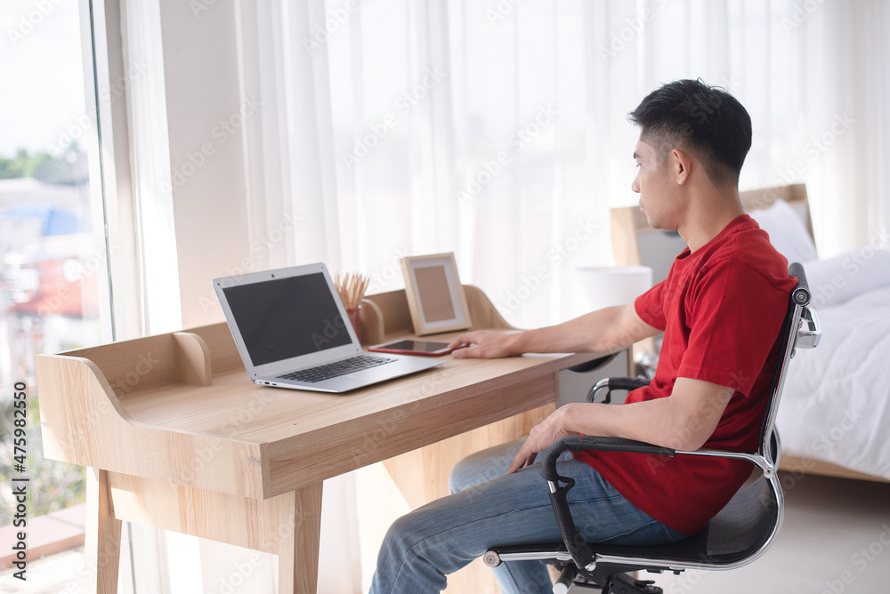 young asian guy do his casual work from his bedroom young asian guy do his casual work from his bedroom