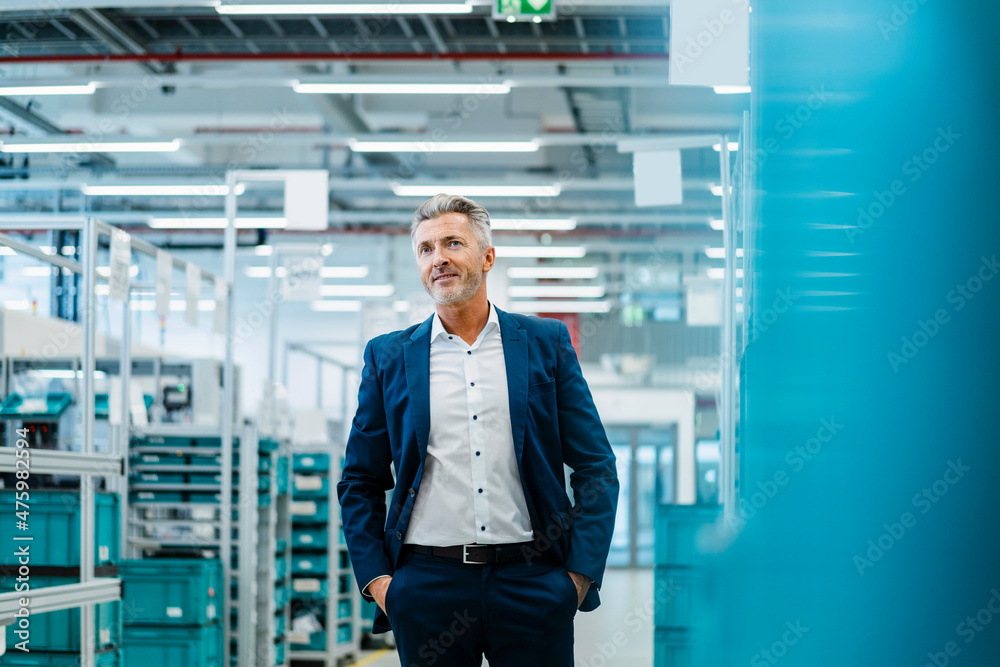 Businessman with hands in pockets at warehouse