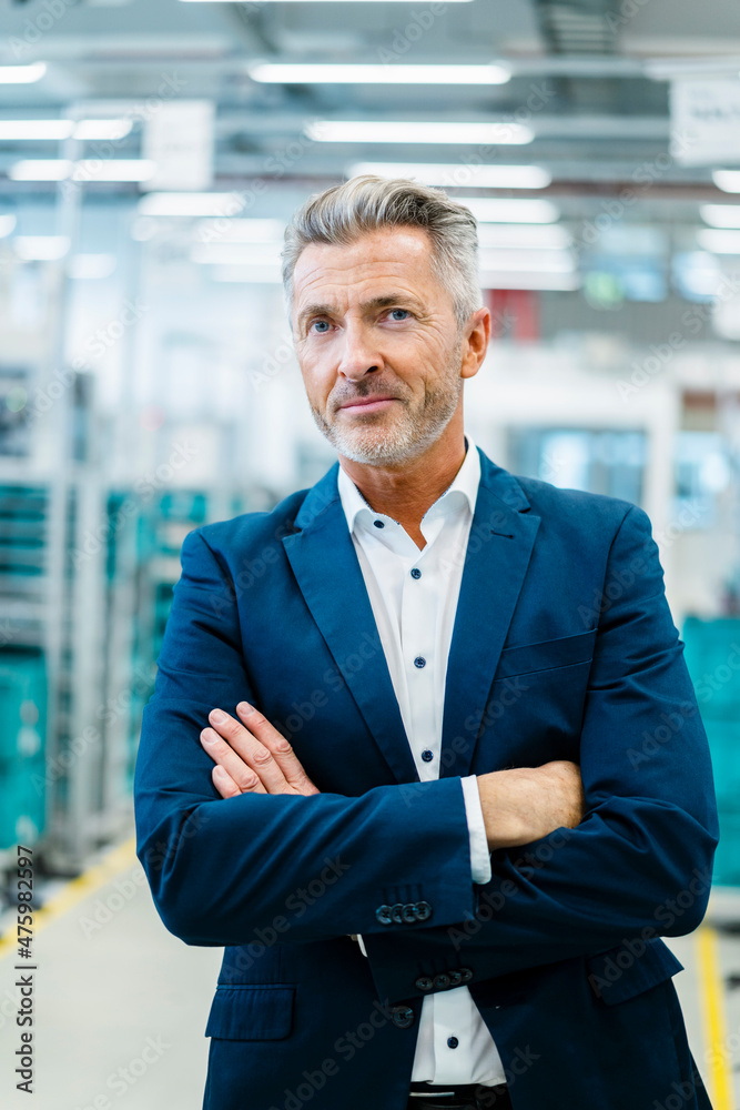 Businessman with arms crossed at automated factory Businessman with arms crossed at automated factory
