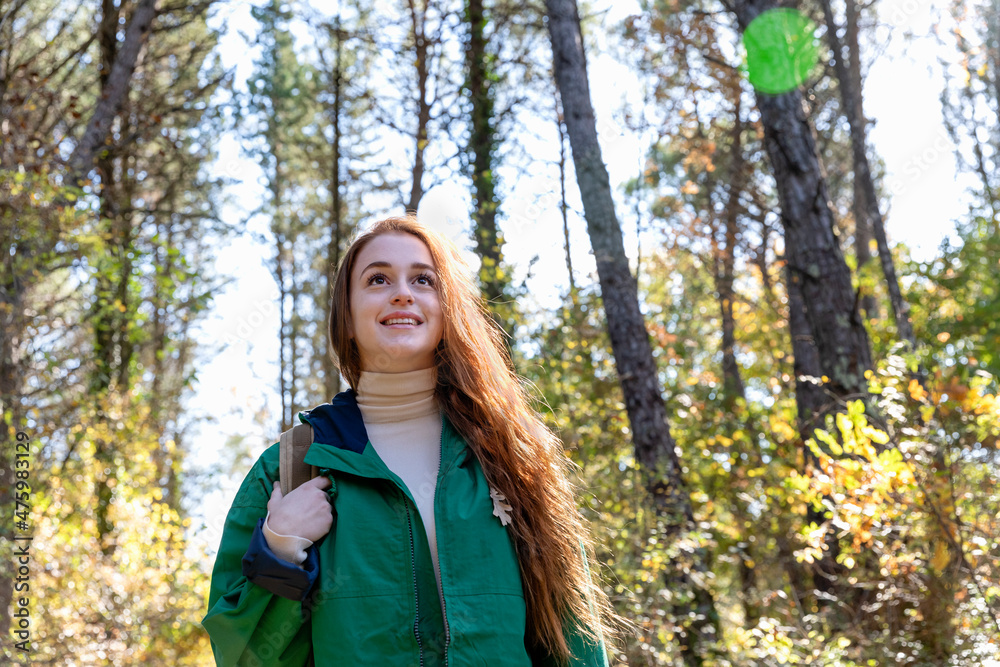 Thoughtful woman looking away while trekking in forest Thoughtful woman looking away while trekking in forest