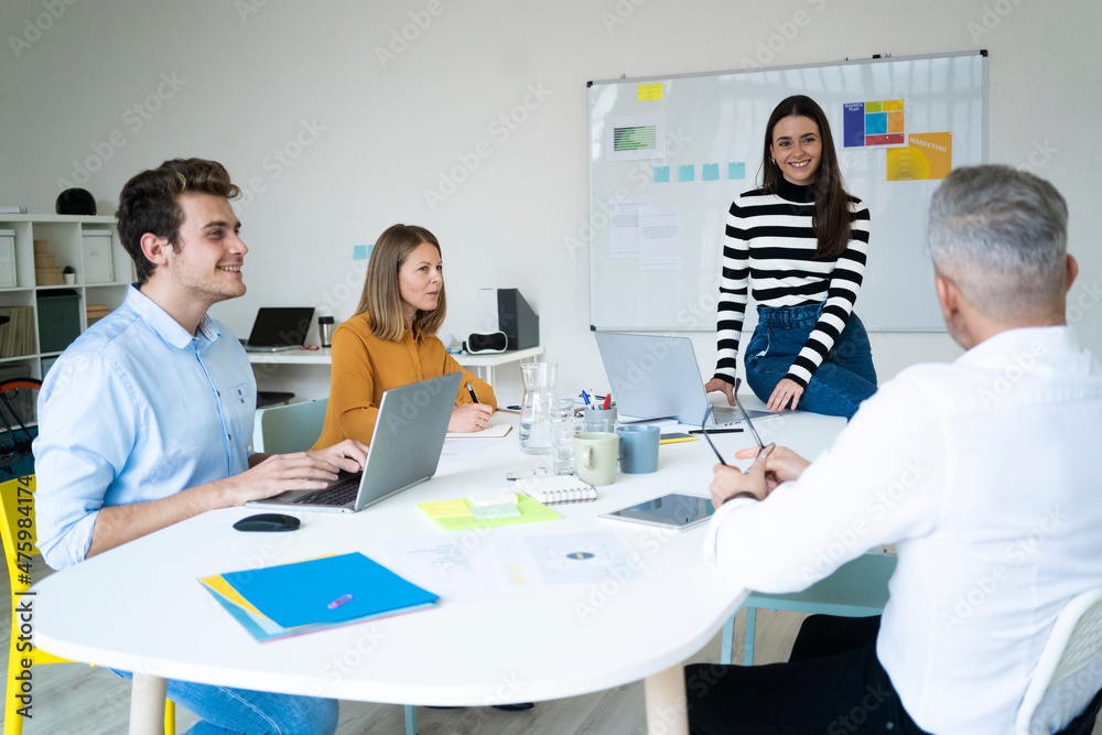 Coworkers discussing with each other at office Coworkers discussing with each other at office
