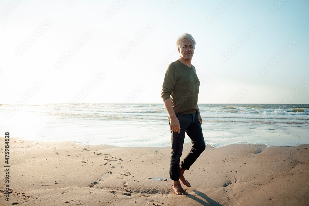 Senior man walking on sand at beach Senior man walking on sand at beach