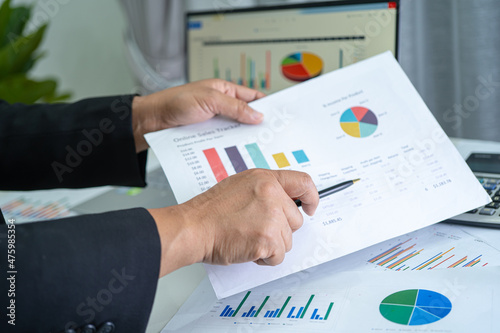 Asian accountant working and analyzing financial reports project accounting with chart graph and calculator in modern office, finance and business concept.