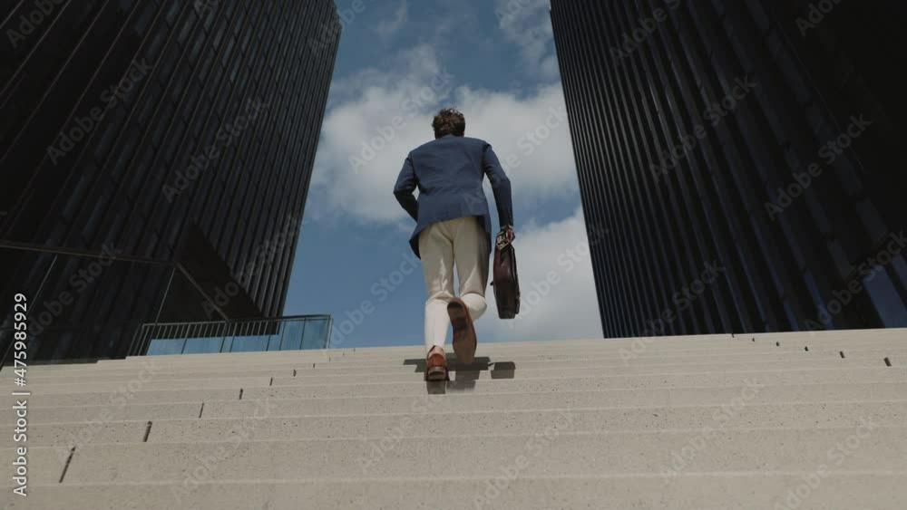 Businessman with suitcase walking up on stairs
