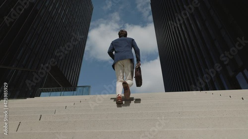 Businessman with suitcase walking up on stairs