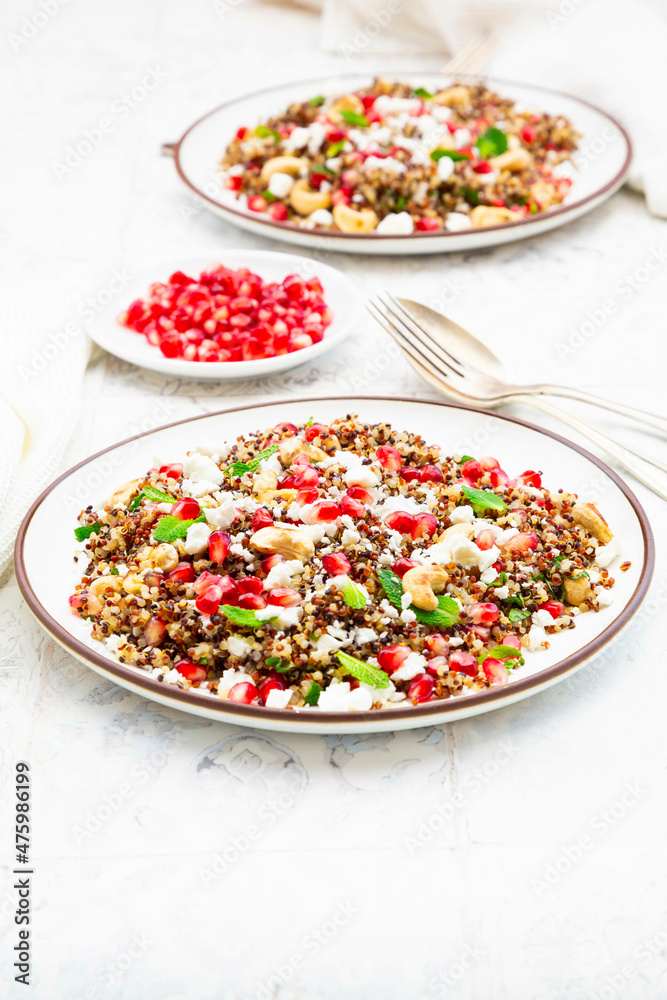Studio shot of two plates of quinoa salad with feta cheese, pomegranate seeds and cashews Studio shot of two plates of quinoa salad with feta cheese, pomegranate seeds and cashews