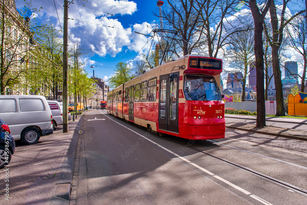 THE HAGUE, NETHERLANDS - APRIL 30TH, 2015: Colorful tram speeds up along the city streets on a beautiful spring day.