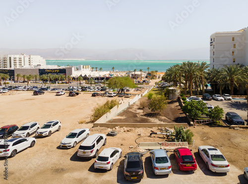 Aerial view from a drone of the beach on the Ein Bokek embankment on the coast of the Dead Sea, tourist hotels and car parks, the sea itself and the mountains of Jordan visible in distance, in Israel photo