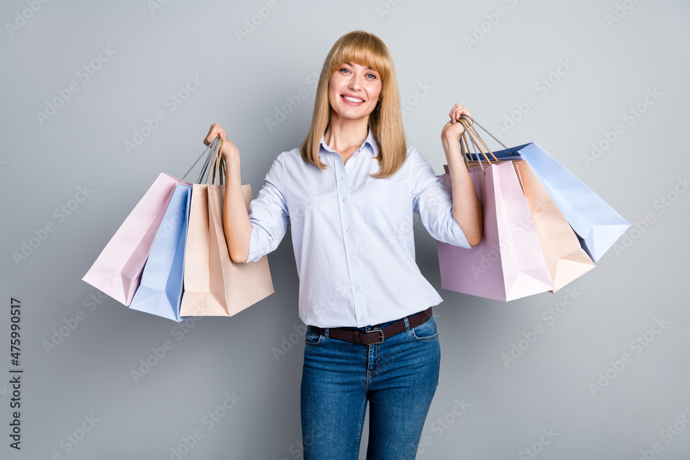 Photo of shiny cute woman wear formal shirt holding shopping bags isolated grey color background Photo of shiny cute woman wear formal shirt holding shopping bags isolated grey color background